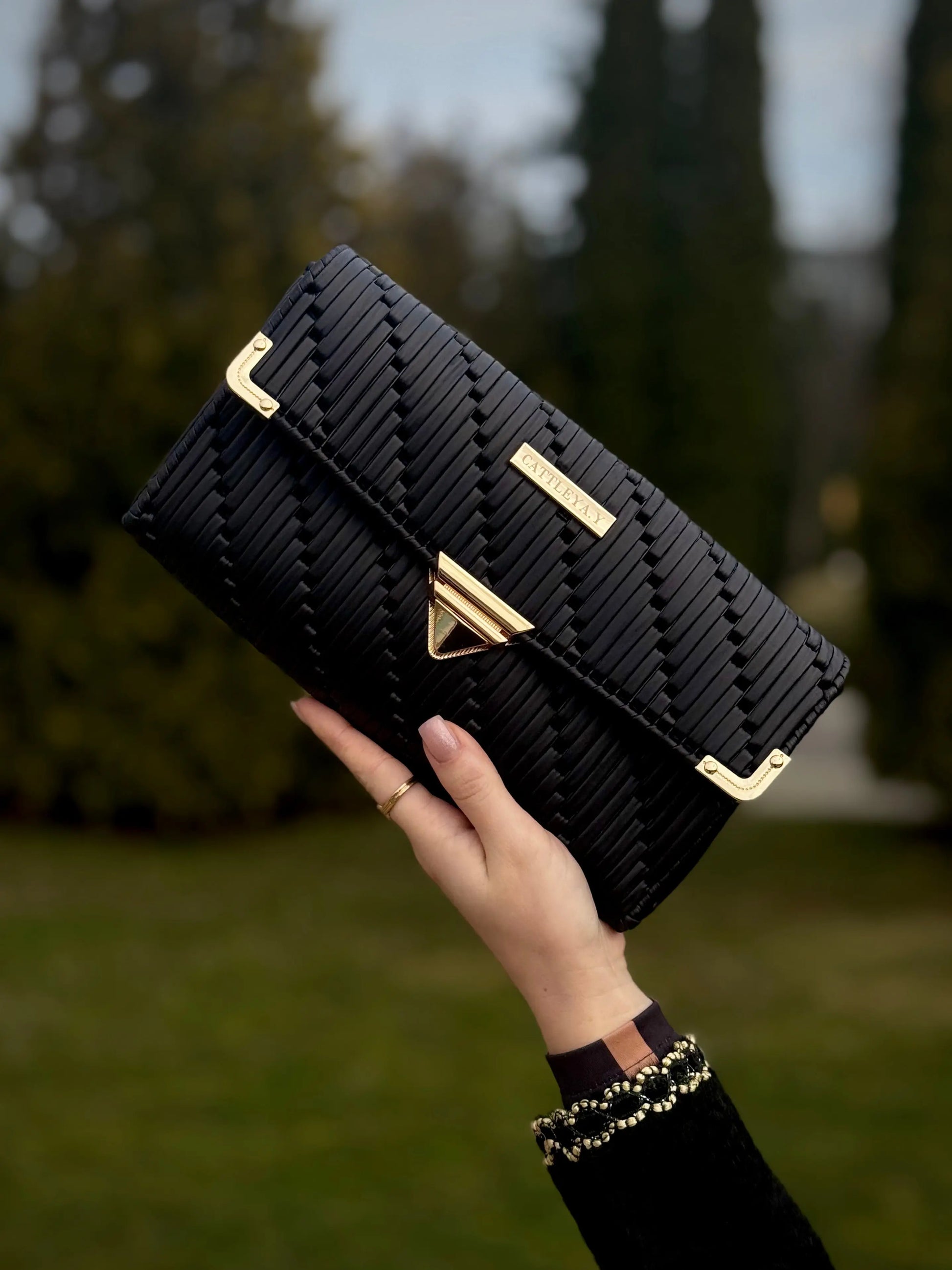 Tiffany is a black luxury handmade designer bag by CATTLEYA.Y front view with gold hardware
