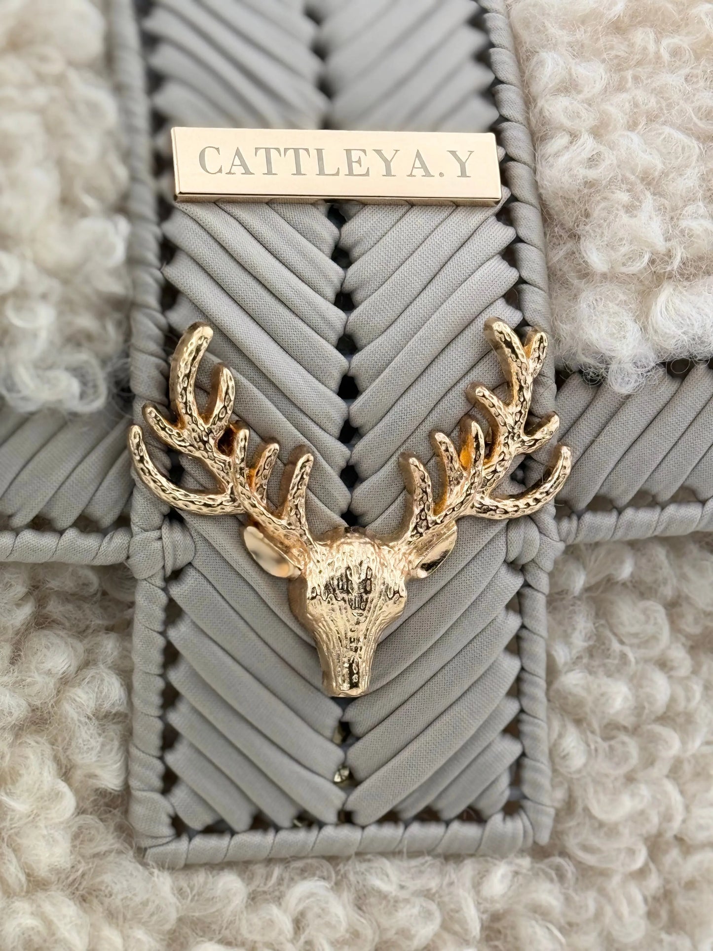 Vivian is a luxury handmade designer bag by CATTLEYA.Y, created for women who appreciate refined winter elegance. The combination of eco-leather yarn and soft bouclé texture creates depth, contrast and sophisticated character.
Gold-tone deer accent detail on Vivian designer bag.