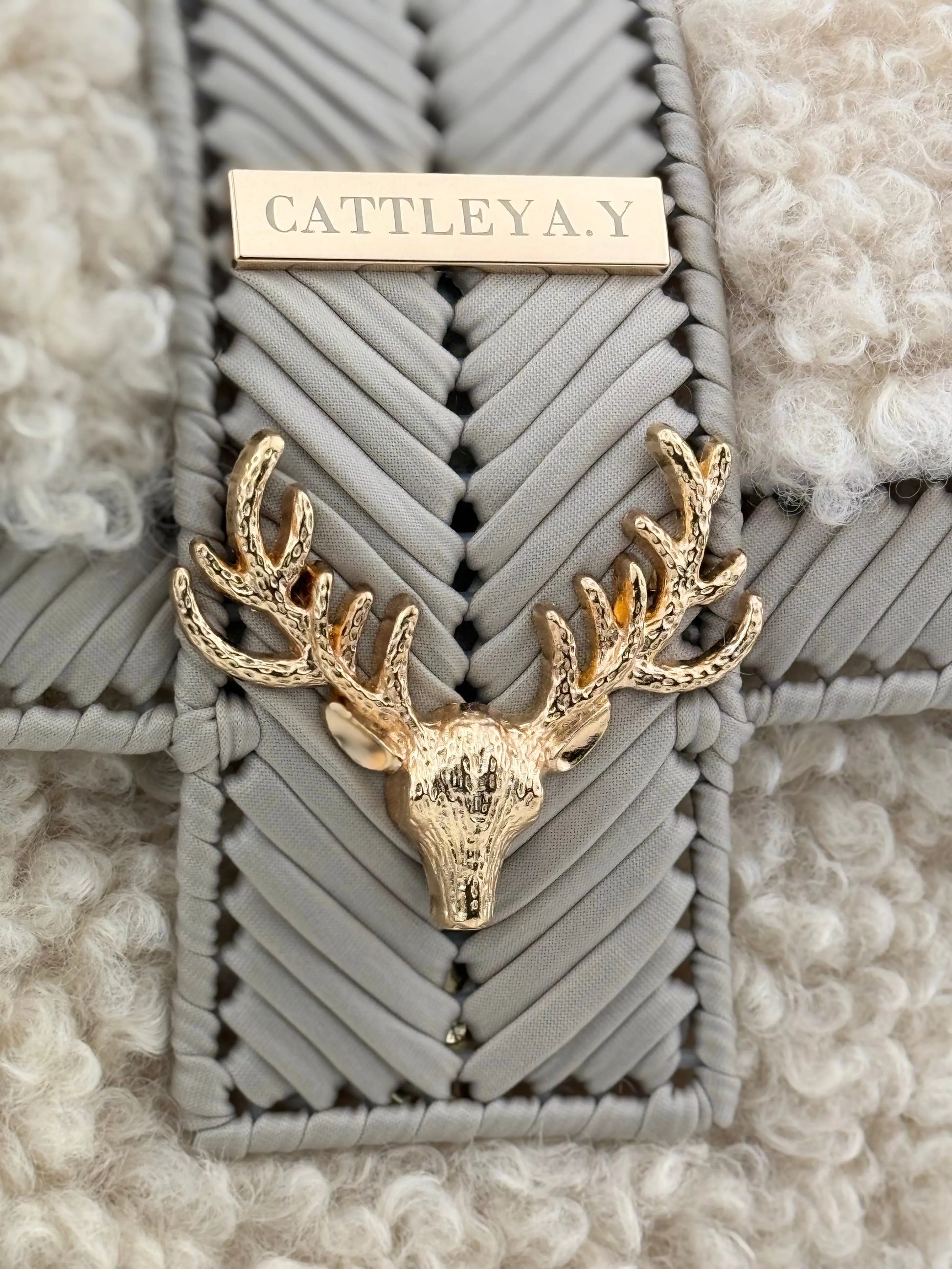 Vivian is a luxury handmade designer bag by CATTLEYA.Y, created for women who appreciate refined winter elegance. The combination of eco-leather yarn and soft bouclé texture creates depth, contrast and sophisticated character.
Gold-tone deer accent detail on Vivian designer bag.